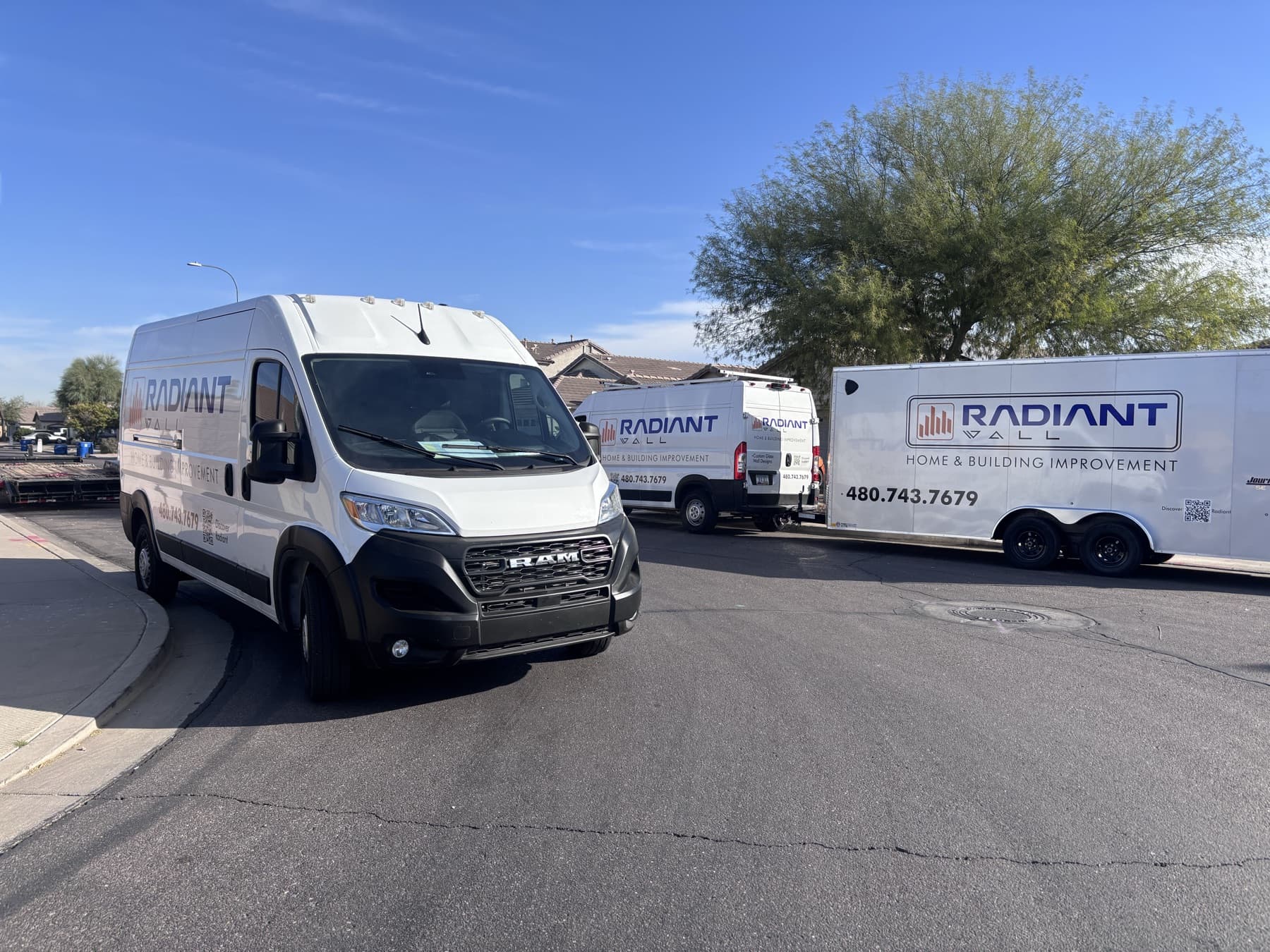 Radiant Wall's branded vans and trailer parked in a Phoenix-metro neighborhood